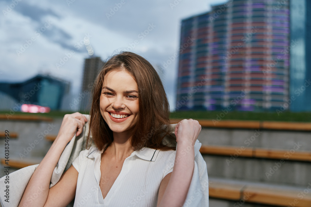 Fototapeta premium Confident woman in business attire smiling outdoors with modern city background, exuding professionalism and positivity in a dynamic urban setting.