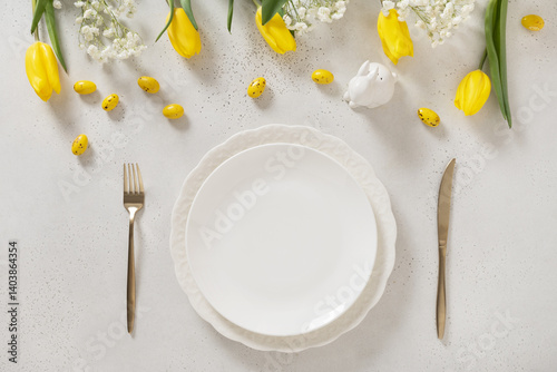 Obraz na płótnie Easter table setting with spring, yellow tulips, white plates, bunny, eggs on white background. Happy Easter celebration. Copy space. View from above. w salonie