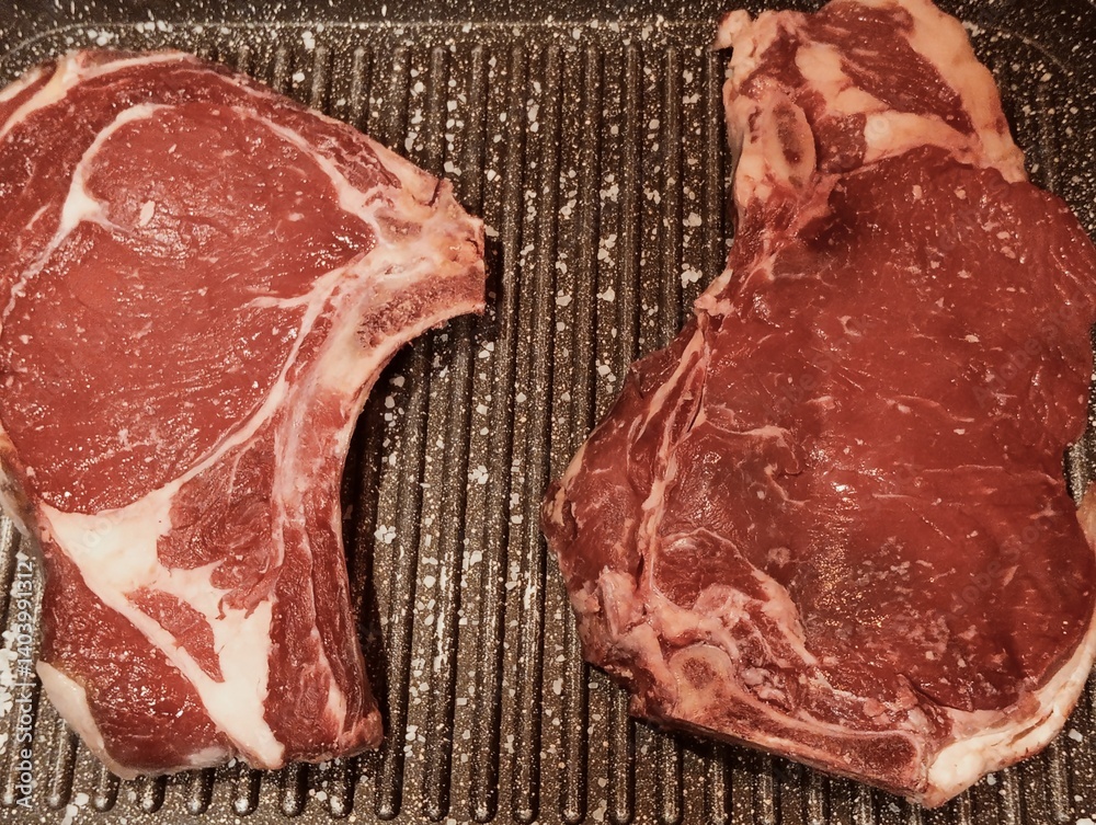 raw beef rib steak cooking on the grill
