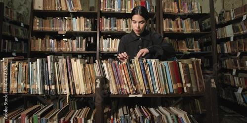 Young woman searching for a book in an old library
