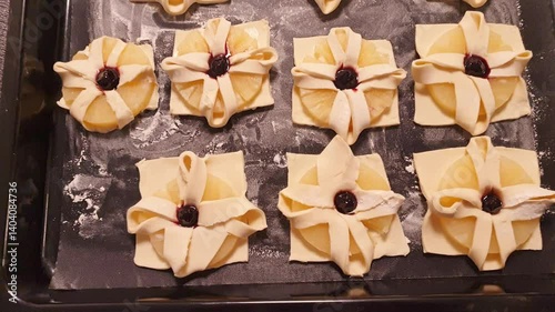 Puff pastry with pineapple wedges wrapped and cherry on top, on the baking tray in the kitchen counter top. Baking