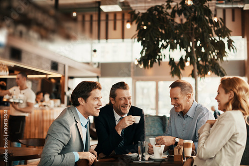 Group of business professionals laughing and networking at coffee shop meeting