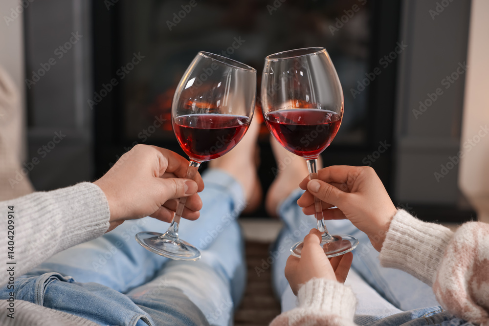 Couple with glasses of wine near fireplace on floor at home, selective focus Couple with glasses of wine near fireplace on floor at home, selective focus