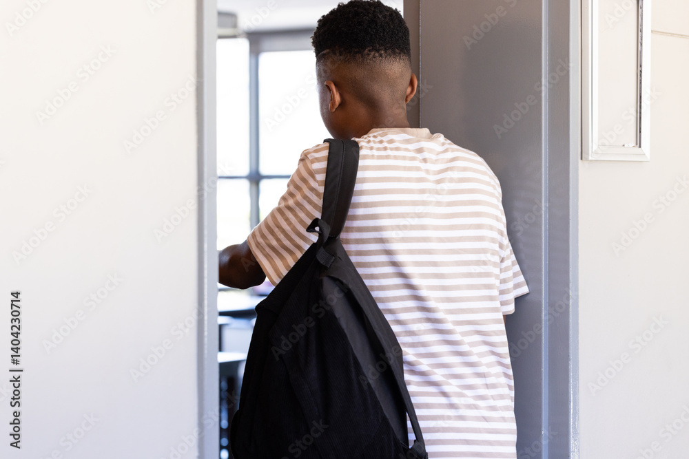 Obraz premium Entering classroom, student with backpack walking through school door