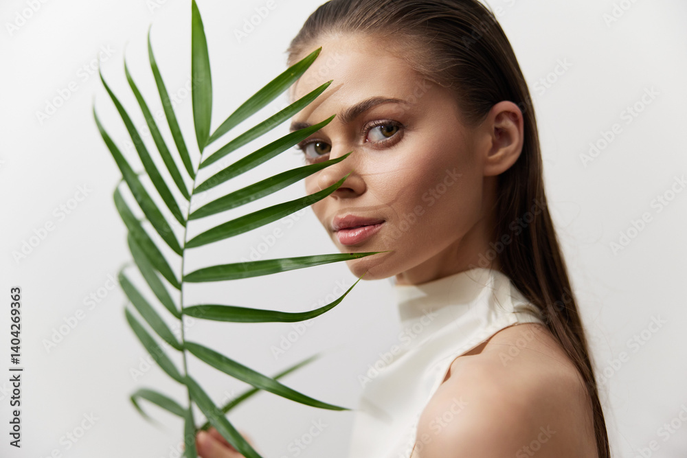 Elegant portrait of a young woman holding a palm leaf, showcasing natural beauty and serenity in a minimalist setting with soft colors. Elegant portrait of a young woman holding a palm leaf, showcasing natural beauty and serenity in a minimalist setting with soft colors.