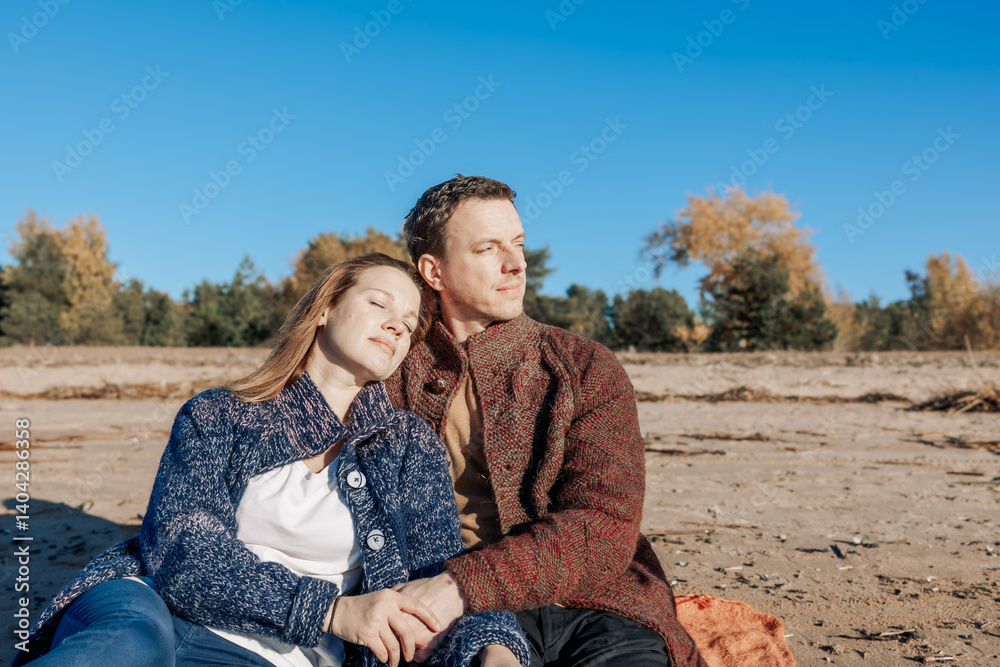 Loving couple walks on beach along sea on sunny autumn day. Weekend and lifestyle concept. High quality photo Loving couple walks on beach along sea on sunny autumn day. Weekend and lifestyle concept. High quality photo