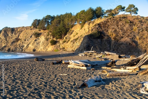 Coastal view of rocky cliffs and sandy beach at sunset in Greenwood Creek State Beach, Elk, California, USA.. Waves crash against the shore, creating a scenic and tranquil landscape.