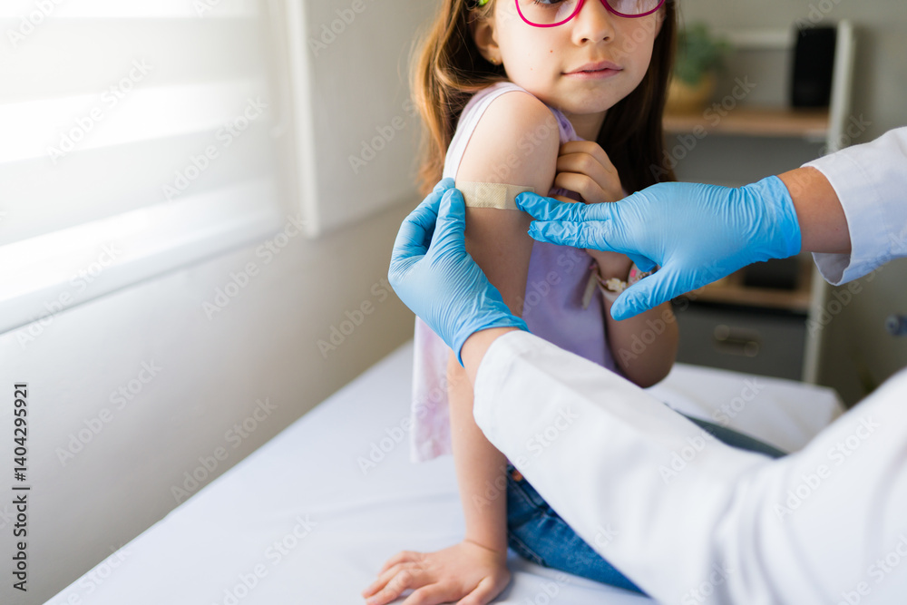 Doctor applying band-aid after vaccine injection on girl's arm in clinic, healthcare and vaccination concept