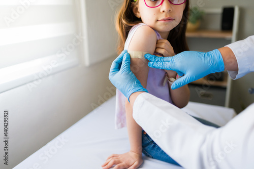 Obraz na płótnie Doctor applying band-aid after vaccine injection on girl's arm in clinic, healthcare and vaccination concept w salonie