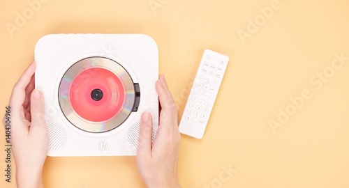 White portable CD player with remote control isolated on peach background. photo