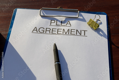 Legal document titled “Plea Agreement” placed neatly on a clipboard set on the desk with pen, representing justice and legal process.