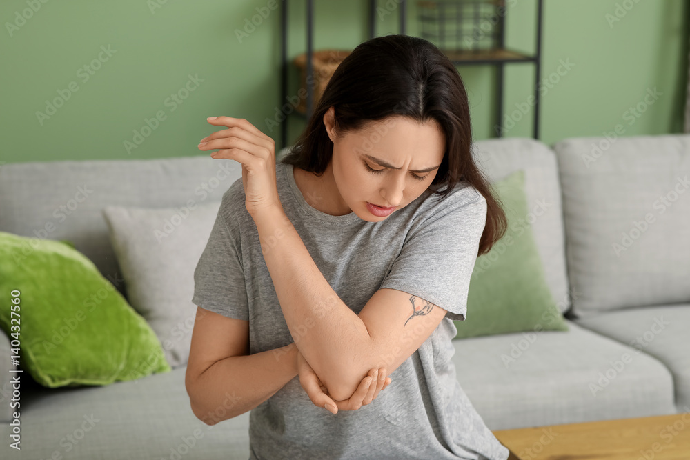 Young woman suffering from pain in elbow at home