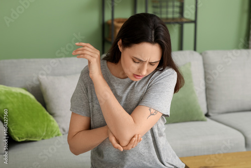 Young woman suffering from pain in elbow at home