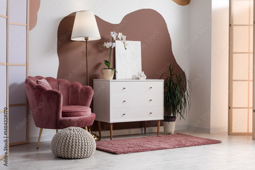 Obraz premium Armchair, chest of drawers, lamp and pouf in interior of living room