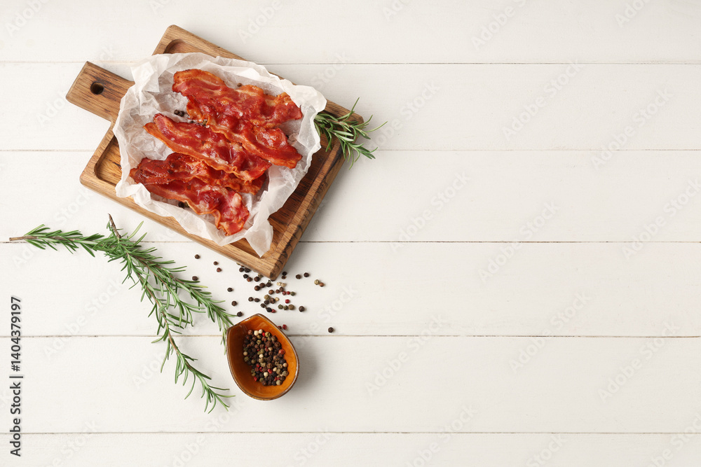 Cutting board with fried bacon rashers, rosemary and bowl of peppercorn on white wooden background