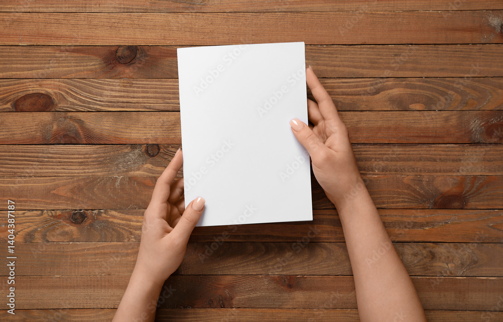 Female hands with blank brochure on wooden background