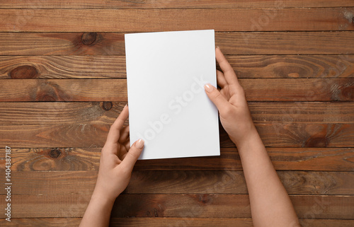 Obraz na płótnie Female hands with blank brochure on wooden background w salonie
