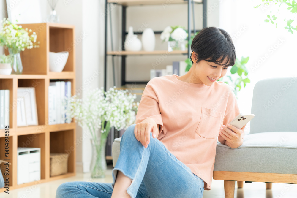 リビングでスマホを見る若い女性 リビングでスマホを見る若い女性