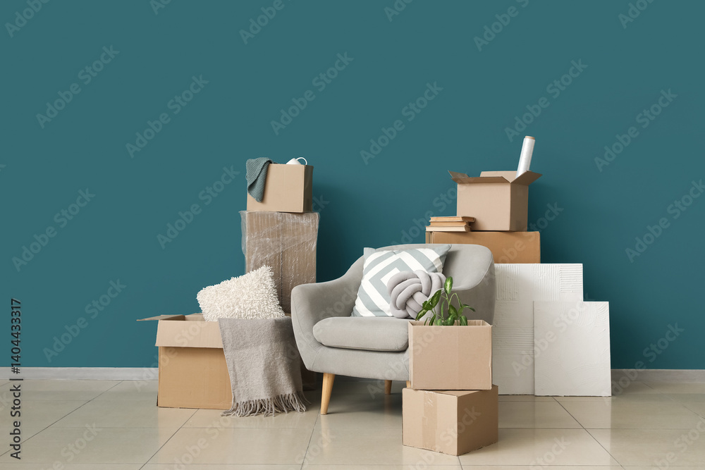 Armchair with cardboard boxes near blue wall in room on moving day