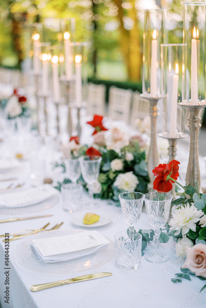 Fototapeta premium Festive set table with flowers and burning candles in a green park