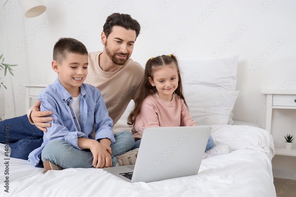 Happy father with his little children watching cartoons on laptop in bedroom Happy father with his little children watching cartoons on laptop in bedroom