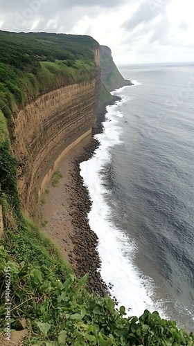 Coastal cliff face with layered rock formations and waves photo
