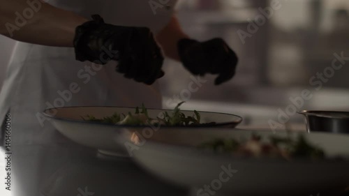 Unrecognizable cook in gloves garnishing meat in plate
