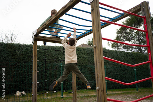 Slika na platnu Children climbing monkey bars on playground structure in backyard