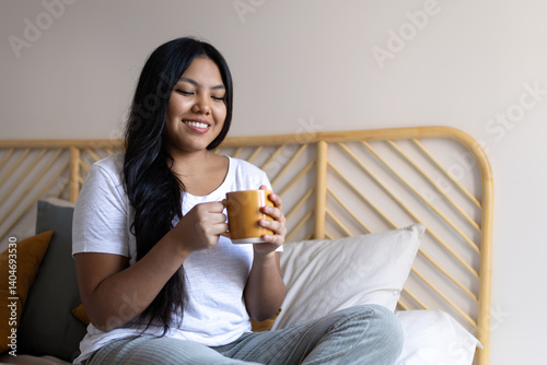 Young latin woman enjoying morning coffee in bed