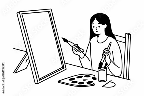Picture of serious concentrated young Caucasian female artist sitting at desk with painting accessories, holding tube of oil paint, mixing colors on palette; unfinished painting on canvas near her