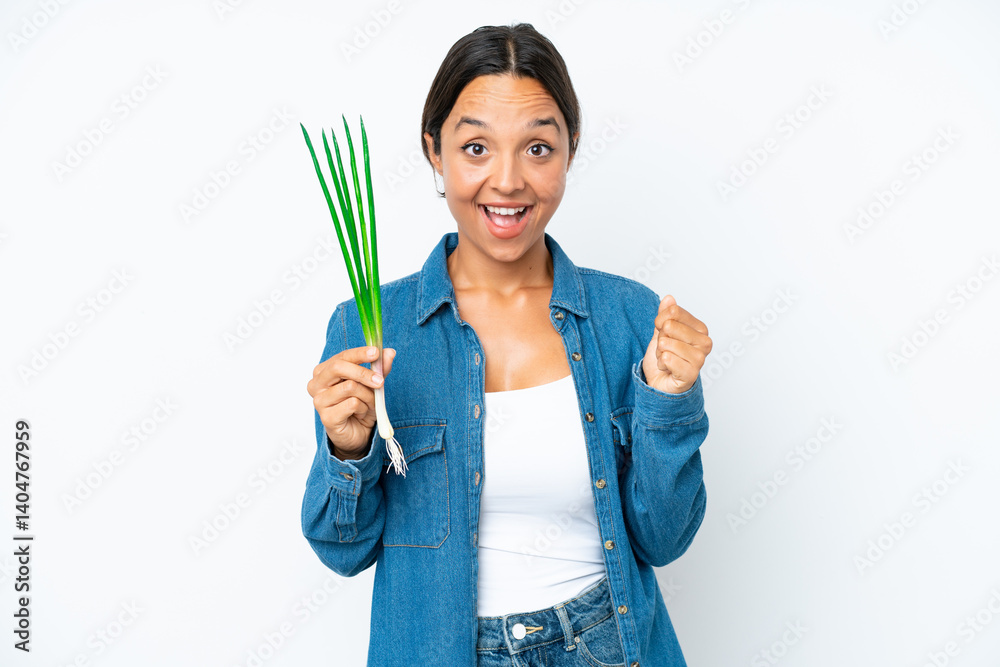 Young hispanic woman holding chive isolated on white background celebrating a victory in winner position Young hispanic woman holding chive isolated on white background celebrating a victory in winner position