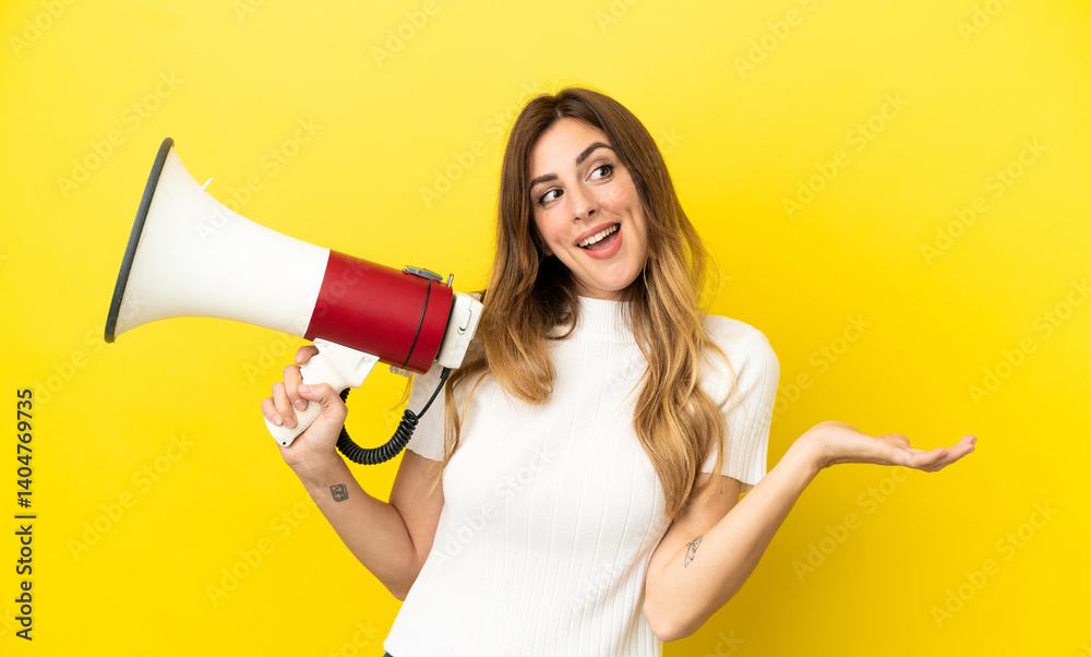 Caucasian woman isolated on yellow background holding a megaphone and with surprise facial expression Caucasian woman isolated on yellow background holding a megaphone and with surprise facial expression