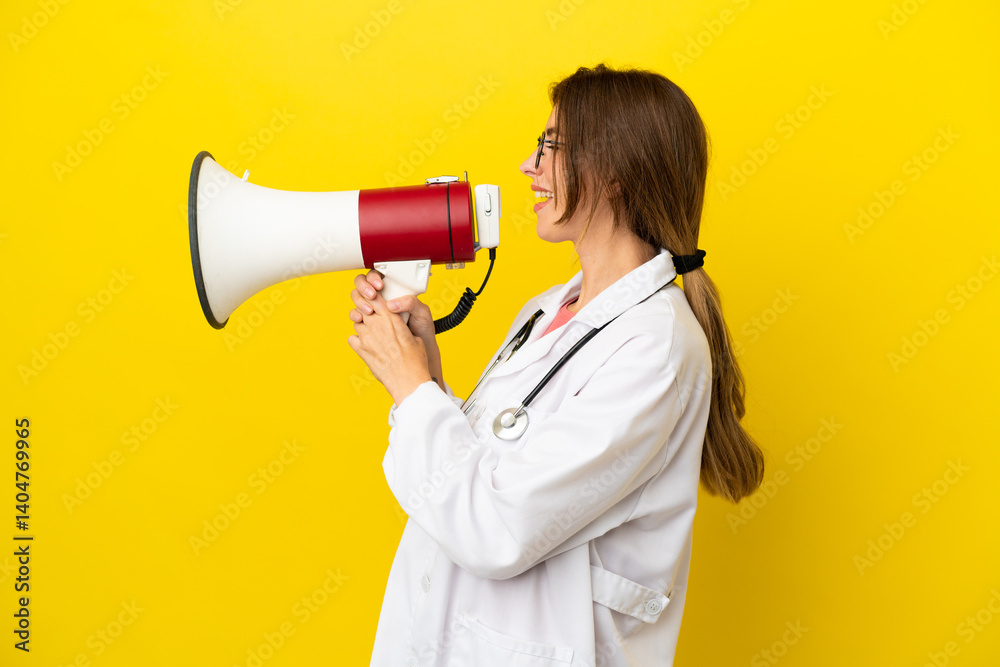 Doctor woman isolated on yellow background shouting through a megaphone Doctor woman isolated on yellow background shouting through a megaphone