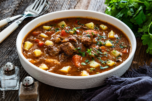 Beef vegetables goulash soup on wooden table