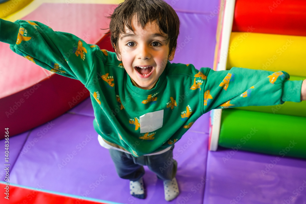 Happy child playing in soft play area with open arms and joyful expression