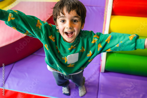 Obraz na płótnie Happy child playing in soft play area with open arms and joyful expression w salonie