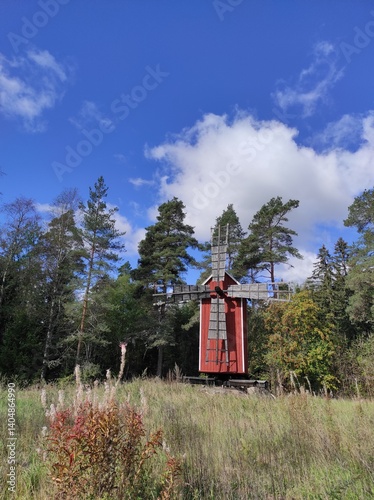 Obraz na płótnie Windmill in the summer forest against the blue sky with clouds w salonie
