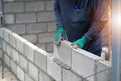masonry worker make concrete wall by cement block and plaster at construction site 
