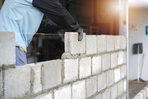 masonry worker make concrete wall by cement block and plaster at construction site 
