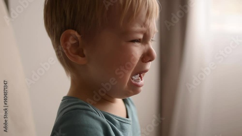Upset toddler crying indoors with tears on cheeks and emotional expression

