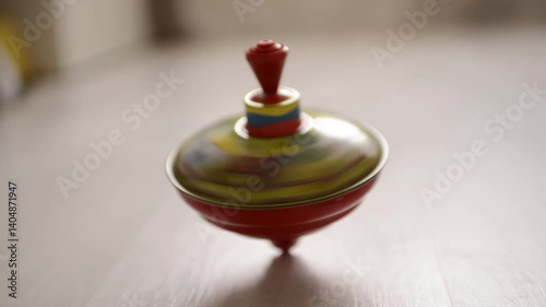 Colorful spinning top toy in motion on a wooden floor with soft natural lighting


