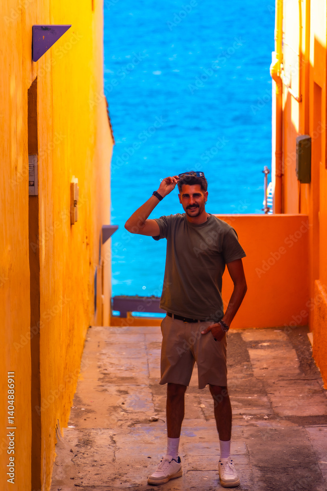 Tourist holding sunglasses in colorful alleyway, gran canaria, spain