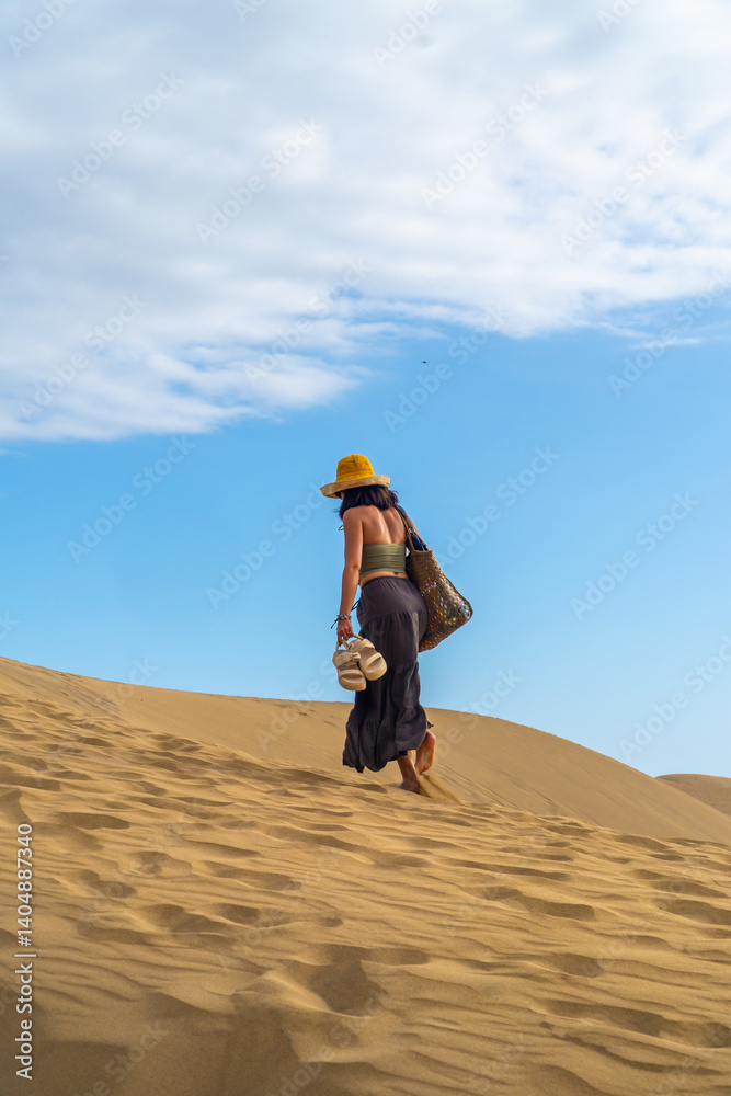 Tourist walking barefoot on maspalomas dunes in gran canaria