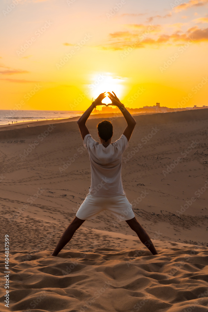 Tourist making heart shape with hands at sunset in maspalomas dunes