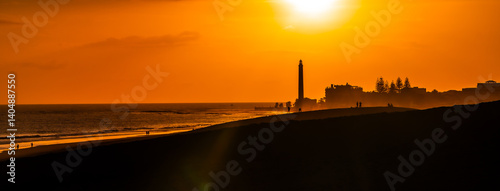 Obraz na płótnie Tourists walking on maspalomas dunes at sunset with lighthouse in background w salonie
