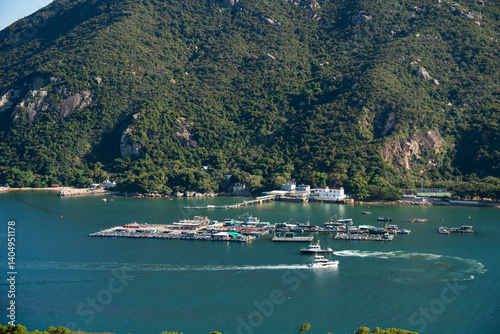 Aerial view of Lamma Island fishing village and floating fish farms in Hong Kong with surrounding green hills and boats on a sunny day