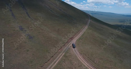 Aerial footage of a black car climbing Mount Armaghan in Madina village, Armenia on a sunny day