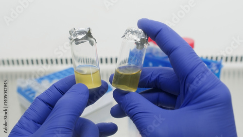 Two small vials with yellow liquid in the hands of a scientist, a laboratory with a sterile space.