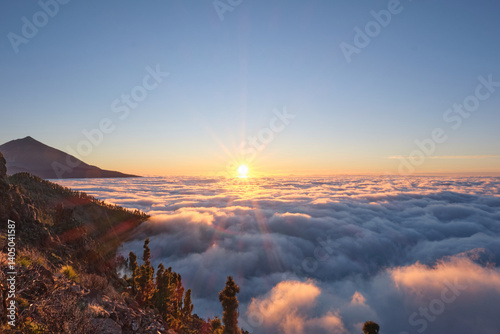 Breathtaking sunrise view over a sea of clouds in Teide National Park, Tenerife, Canary Islands. The silhouette of Mount Teide, Spain's highest volcano, rises in the background as morning light floods