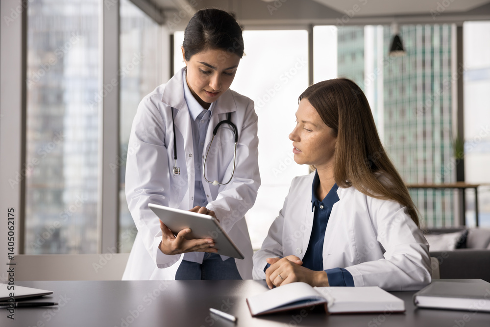 Guidance in medical training. Focused young female medic worker intern get professional advice consultation from experienced colleague mentor learn to read laboratory results looking on tablet screen Guidance in medical training. Focused young female medic worker intern get professional advice consultation from experienced colleague mentor learn to read laboratory results looking on tablet screen